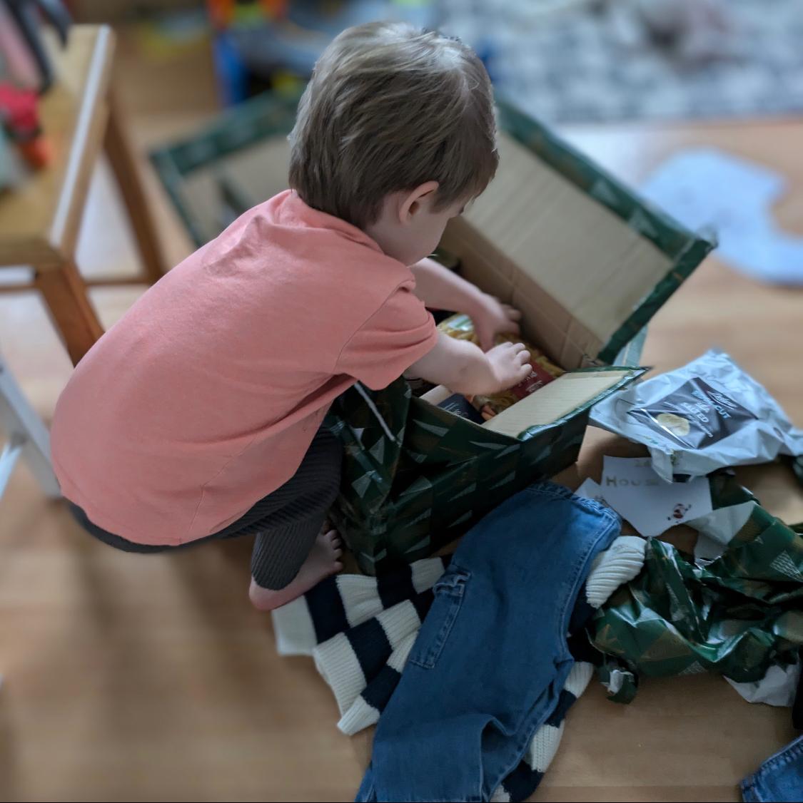 Photo of a child opening a box of Christmas gifts